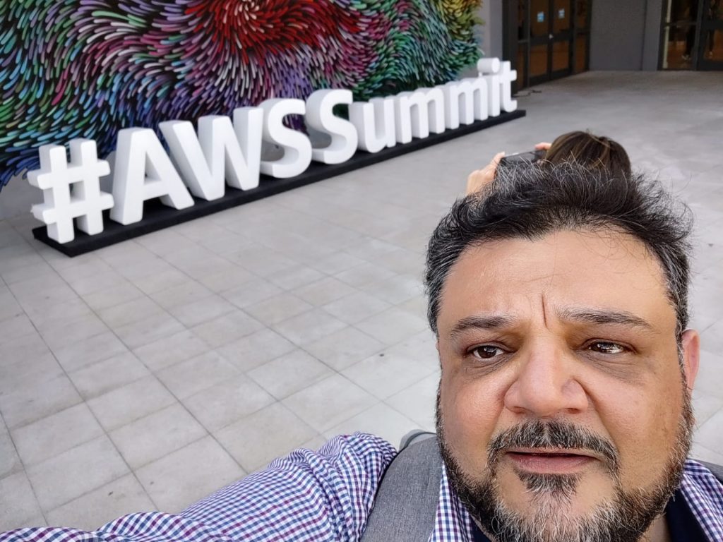 Instrutor tirando selfie a frente da placa #AWSSummit